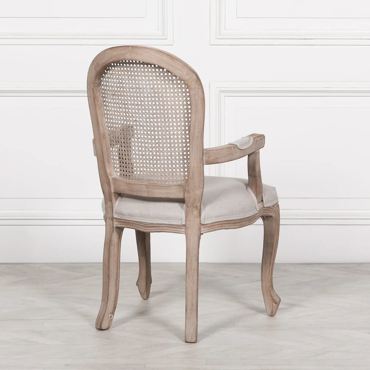 Back view of wooden dining chair with light fabric seat and cane backrest in classic design