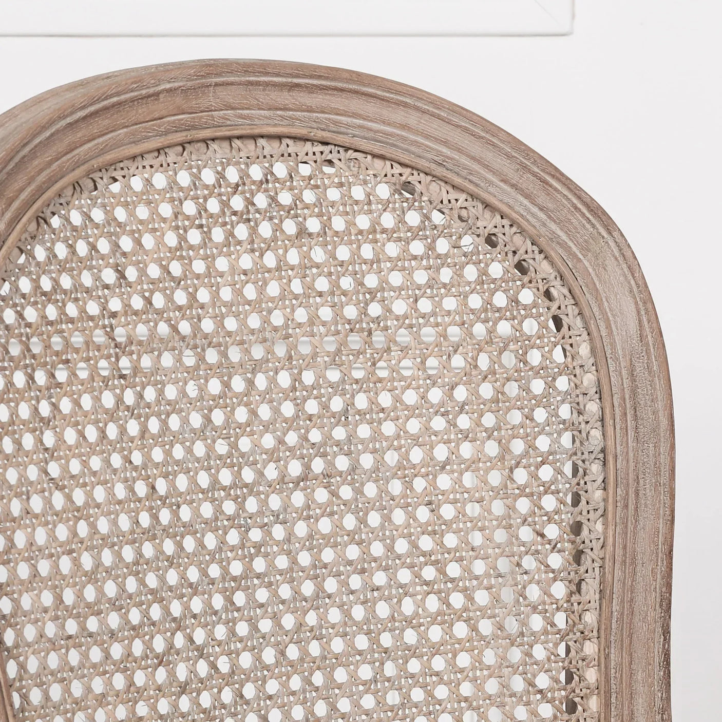 Closeup of natural rattan dining chair back with curved wood frame