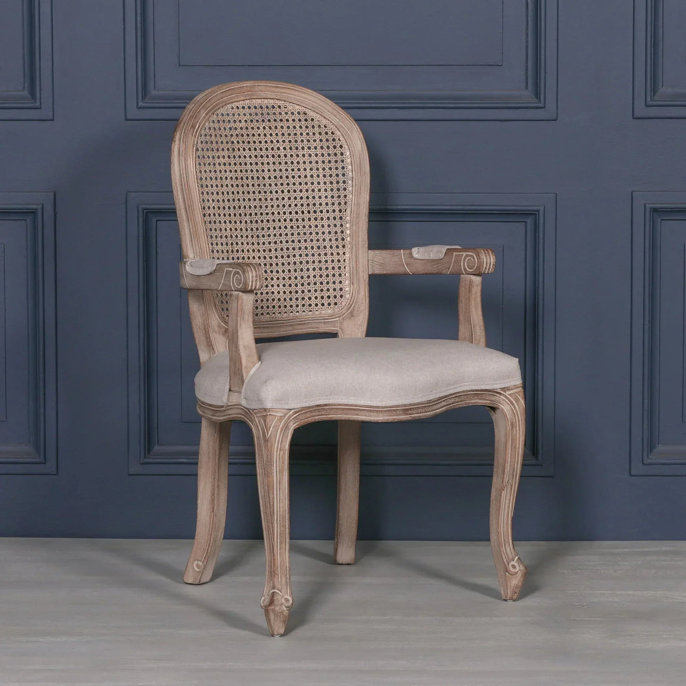 wooden armchair with cane backrest and light fabric seat against navy wall