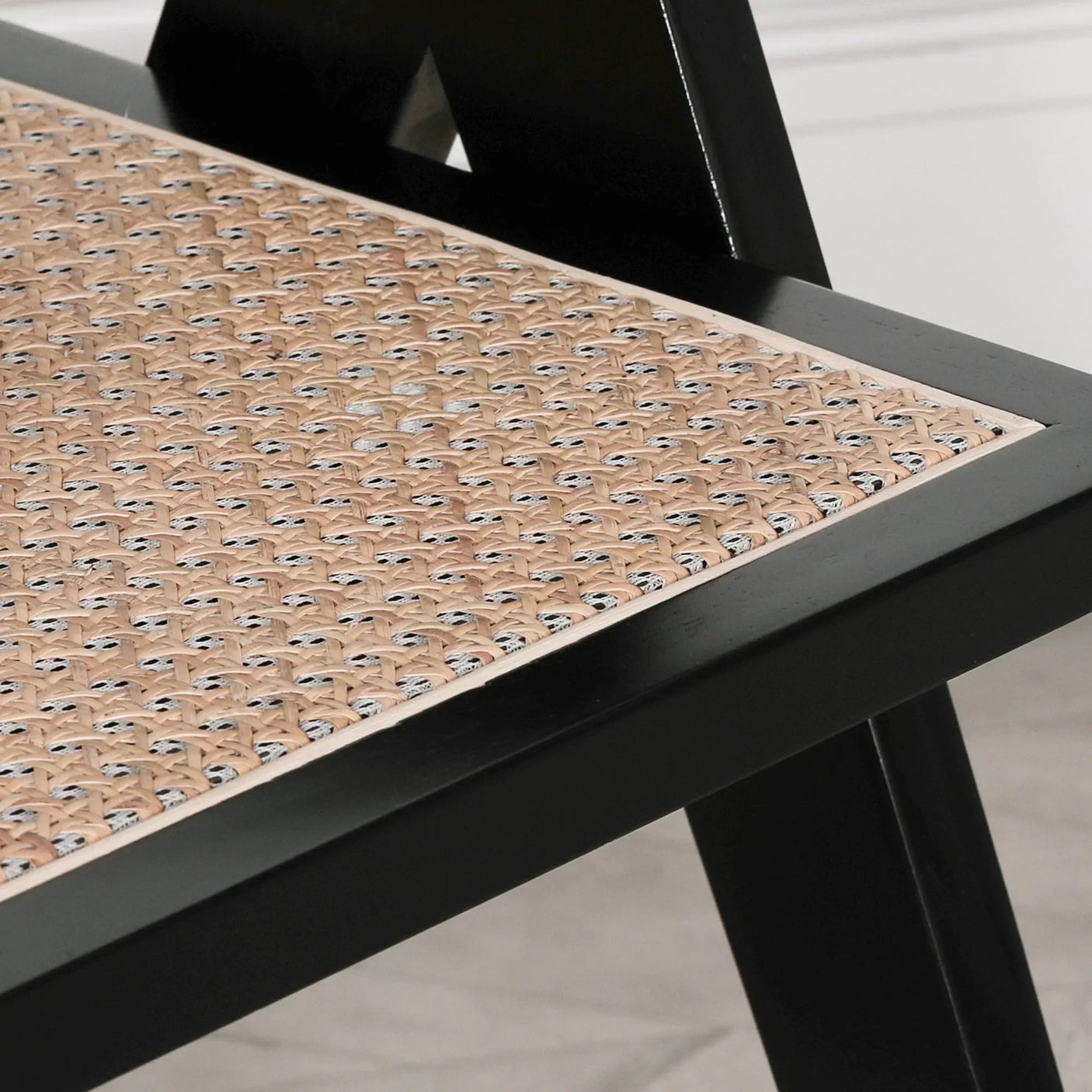 Black wood dining chair corner with natural rattan seat detail