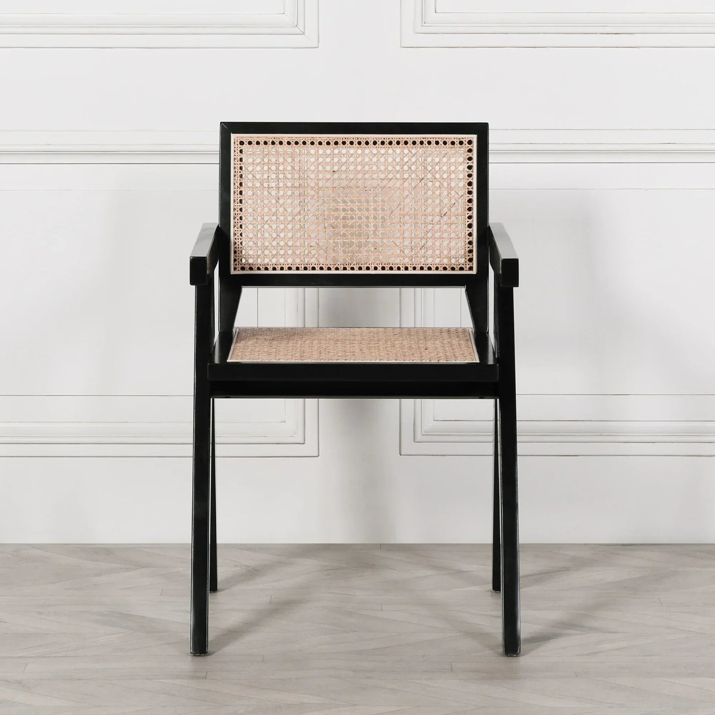 Black wooden dining chair with rattan seat and backrest, shown against a white wall