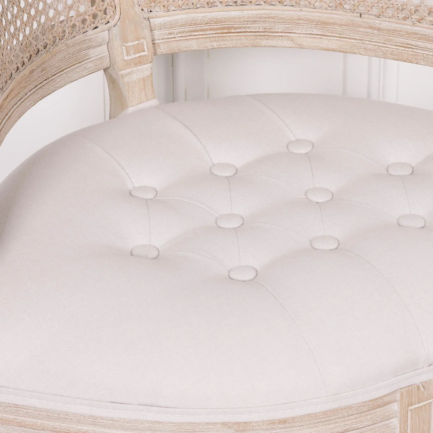 Cream upholstered armchair seat with button-tufted cushion and light wood frame detail