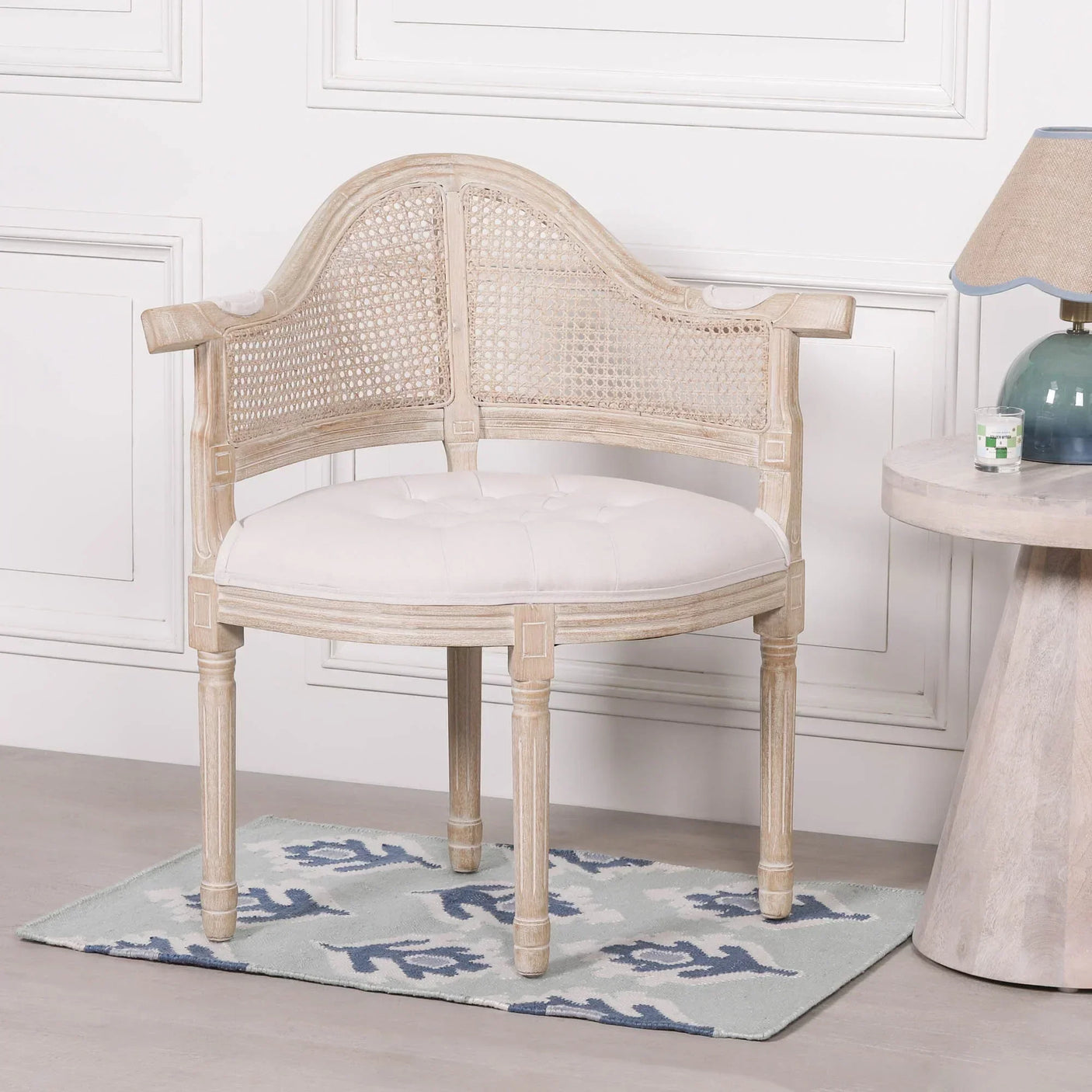 Wooden accent chair with cane backrest and white upholstered seat beside round side table