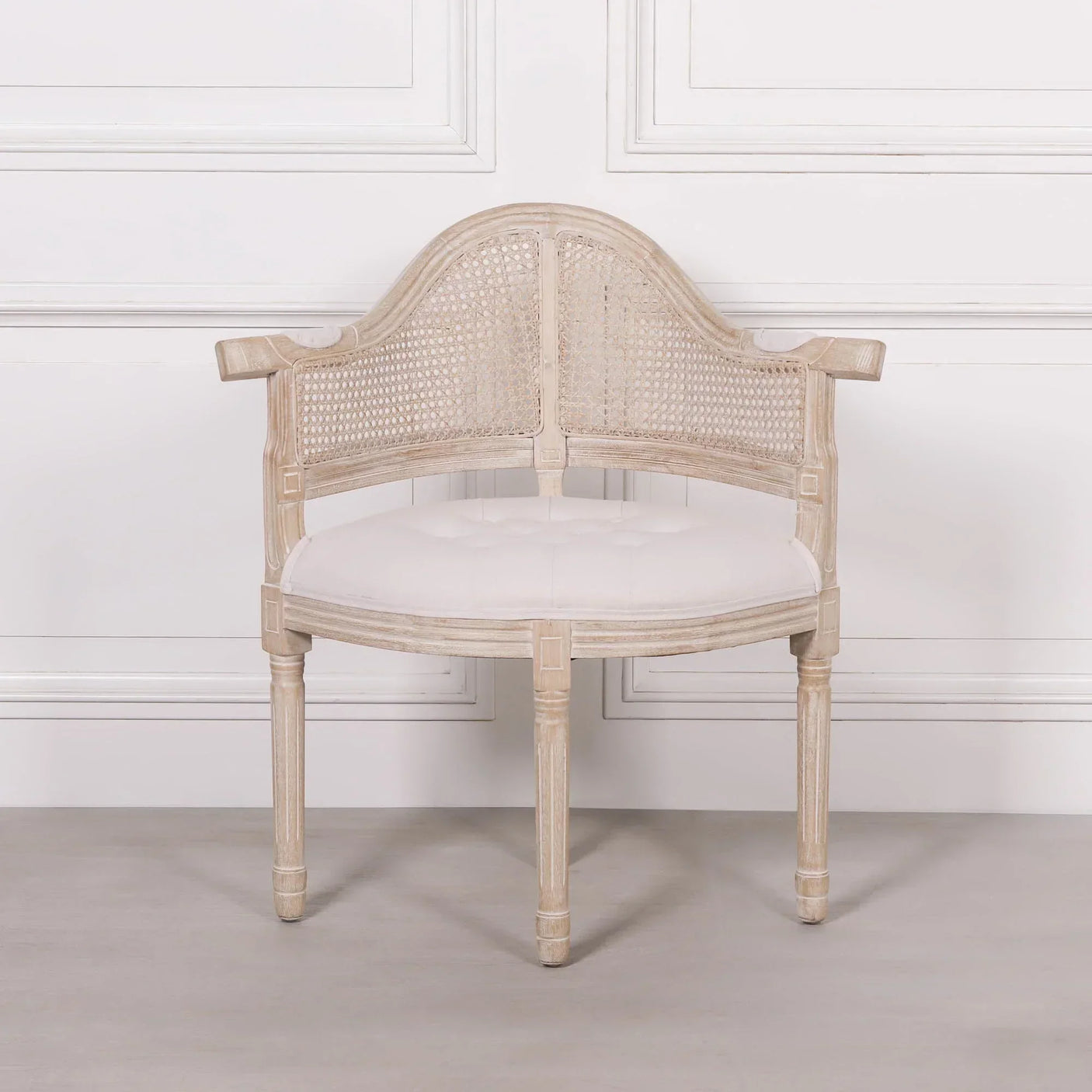 Light wood accent chair with cane backrest and white upholstered seat against a white wall