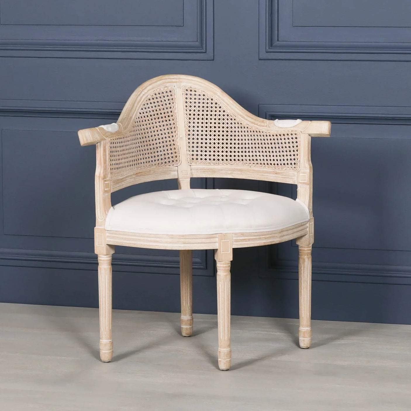 wooden cane-back occasional chair with white upholstered seat against blue panel wall