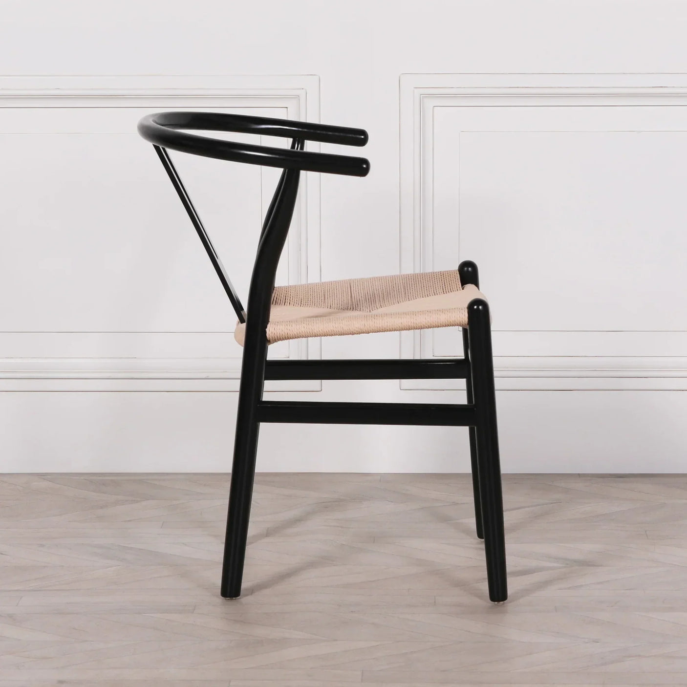black dining chair with curved backrest and woven natural seat side view