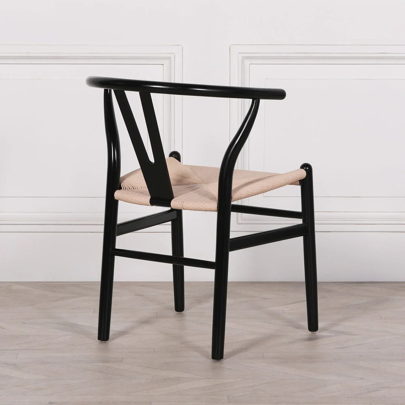 Black dining chair with woven natural seat and curved backrest on wooden floor