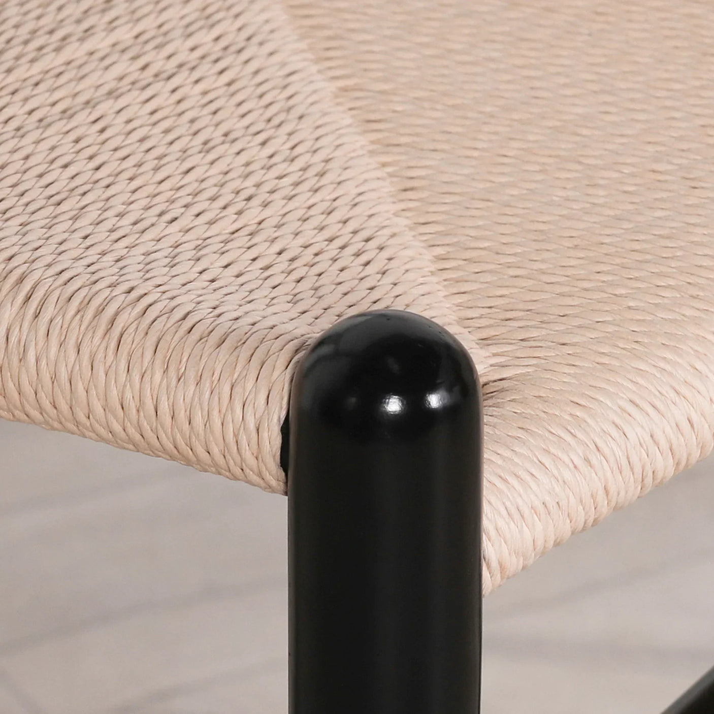 Close-up of woven rope dining chair seat with black metal frame