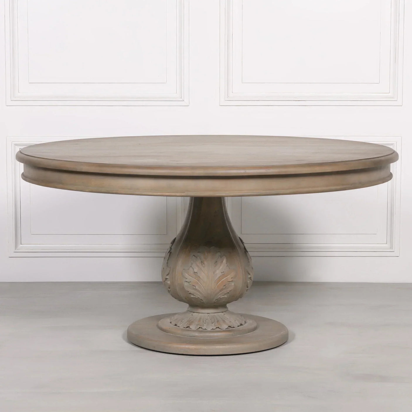 Round wooden dining table with carved pedestal base and light oak finish