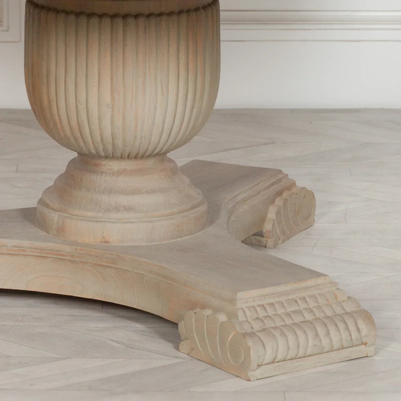 Carved wood dining table base with light finish and fluted pedestal detail