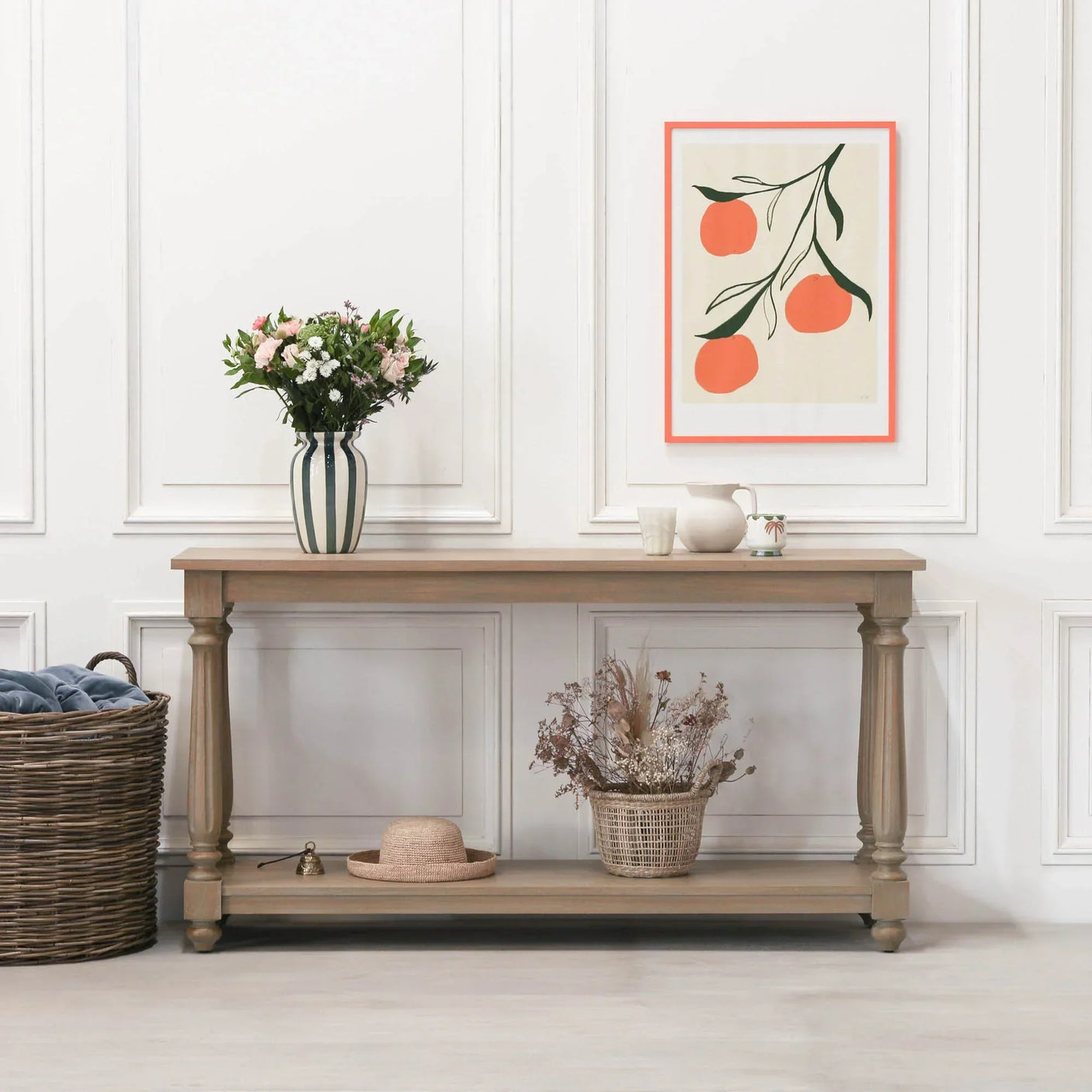 Wooden console table with turned legs, styled with flowers, baskets, and wall art