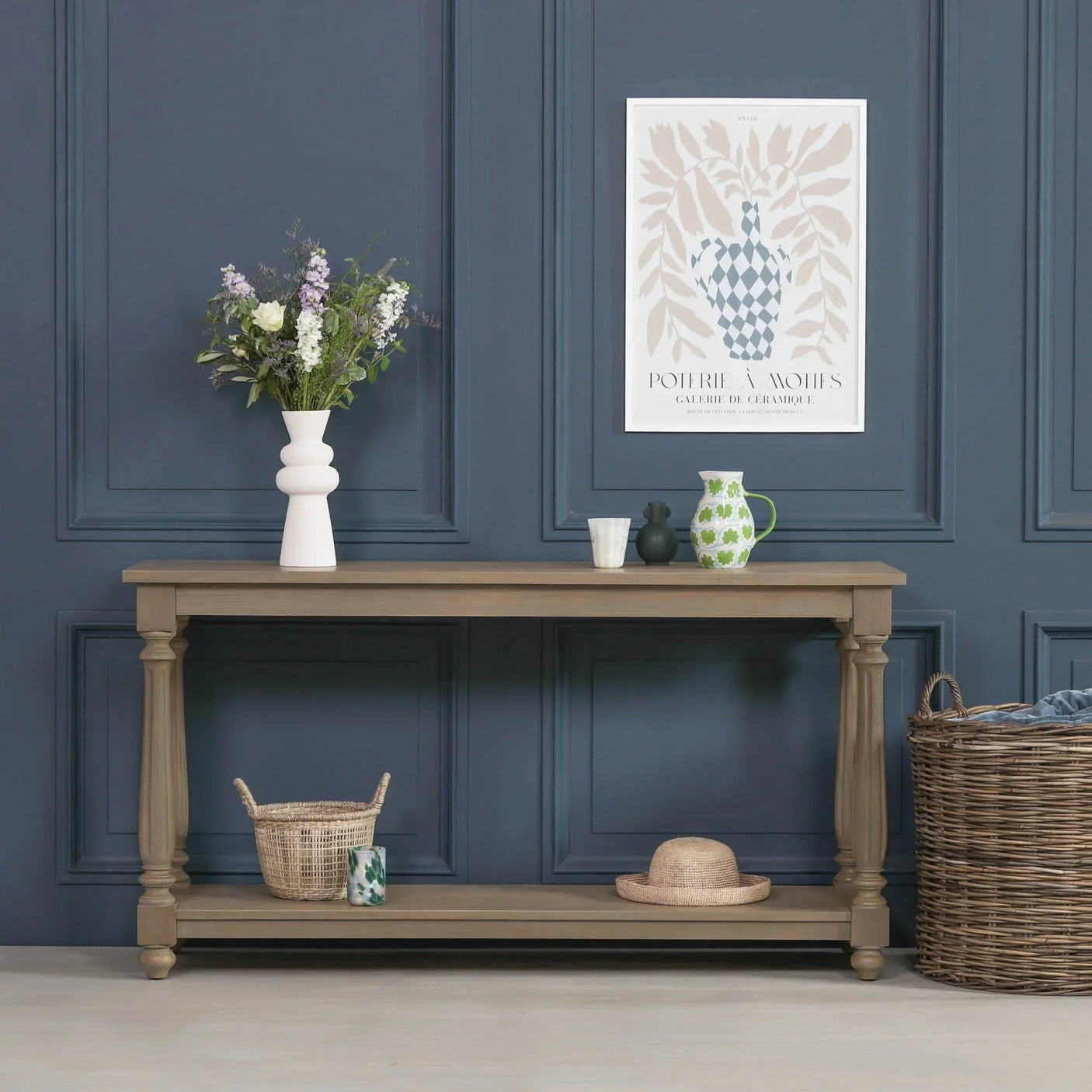Oak console table with vase, decorative items, and lower shelf against blue paneled wall
