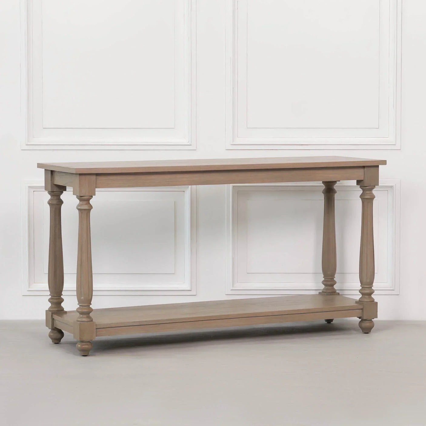 Oak console table with turned legs and lower shelf against white panelled wall