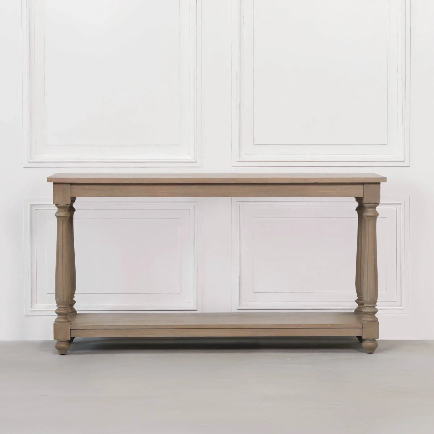 Oak console table with turned legs and lower shelf against white wall paneling
