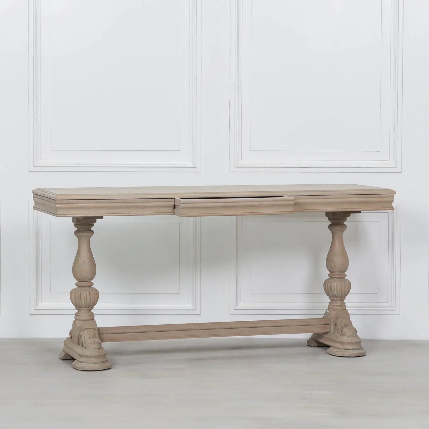 Oak dining table with carved pedestal legs against white panelled wall
