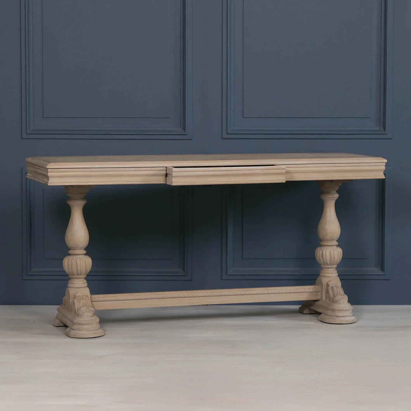 Oak console table with carved legs against dark blue paneled wall