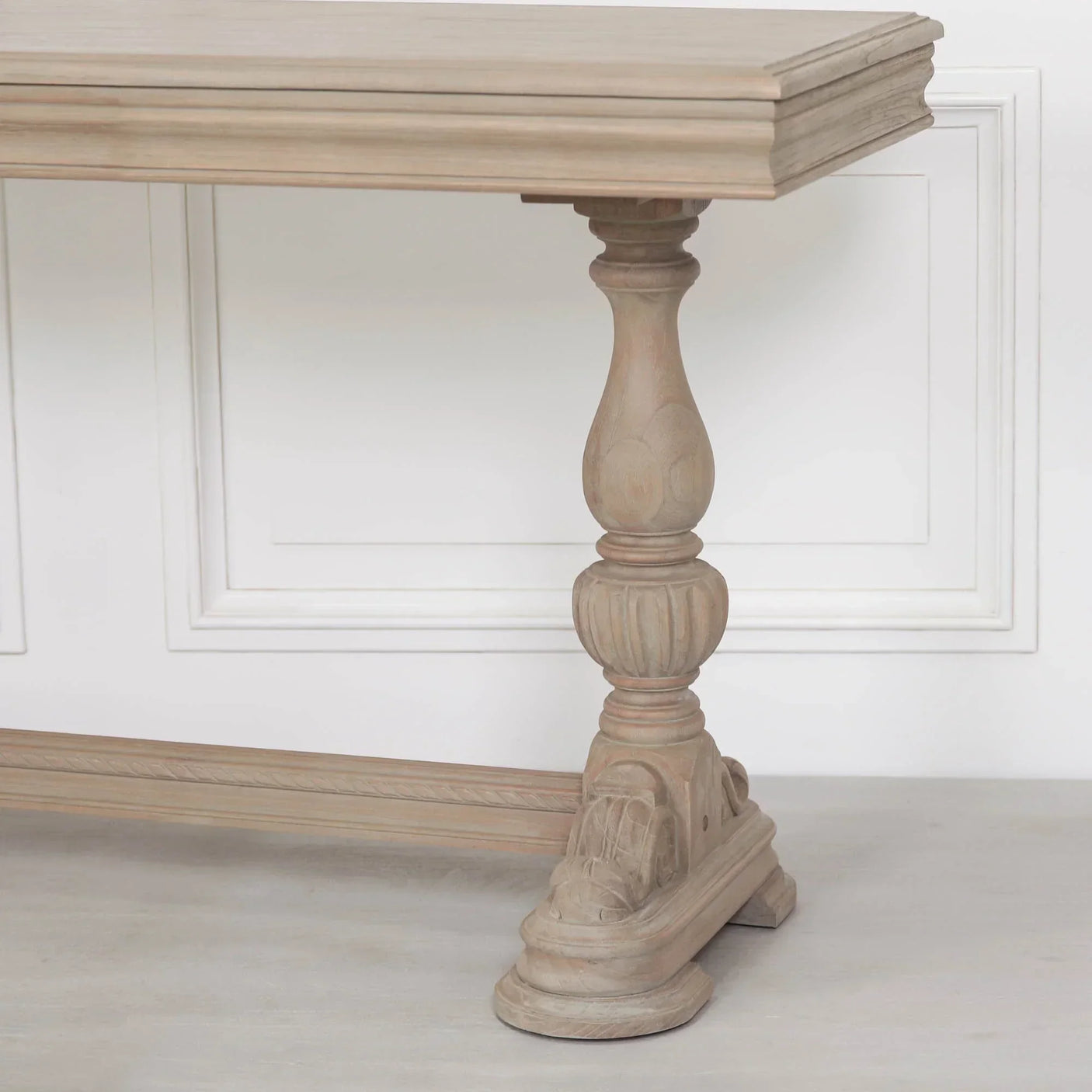 Close view of wooden dining table with carved pedestal base and natural finish