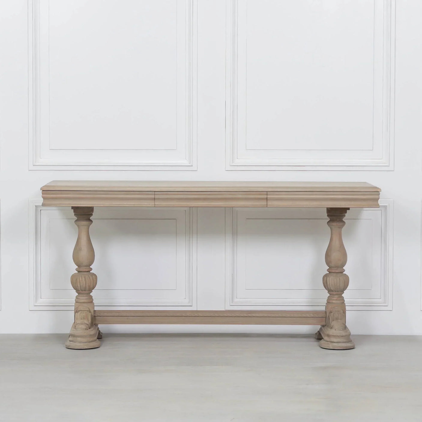 Light wood console table with carved turned legs against a white panelled wall