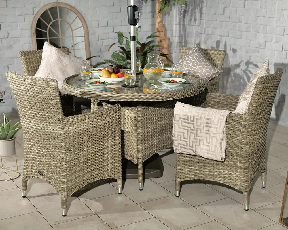 Rattan outdoor dining set with glass-top table, four armchairs, and neutral cushions