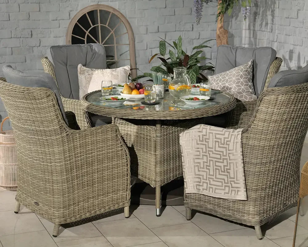 Rattan garden dining set with glass top table, four cushioned armchairs and tableware