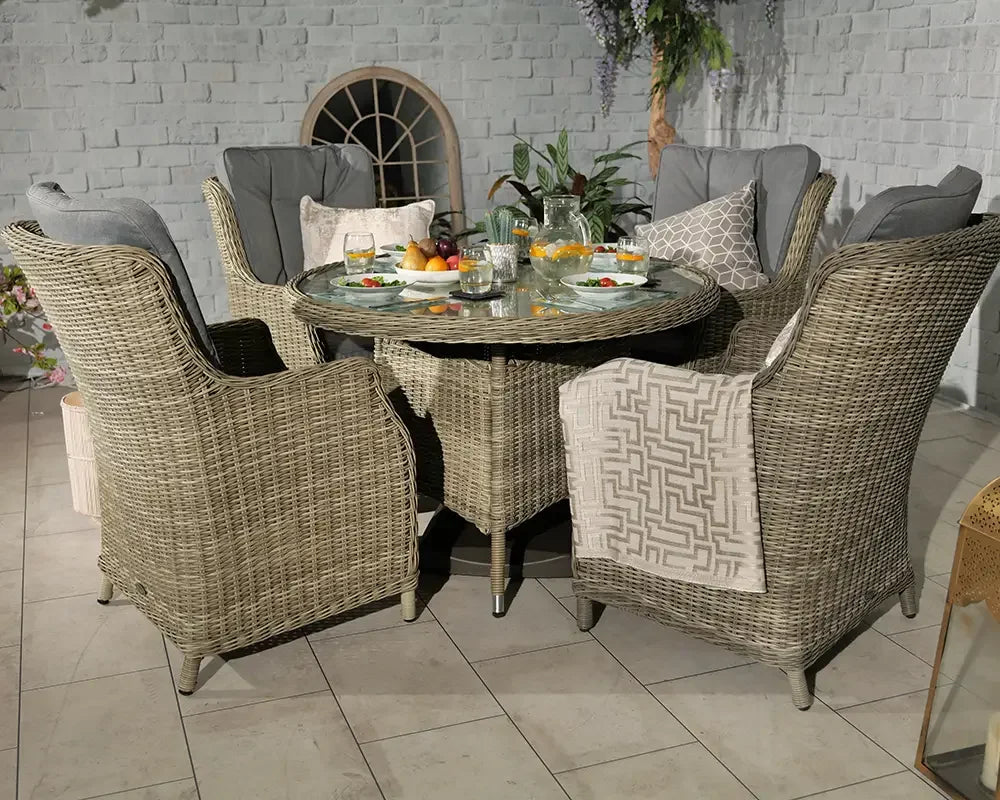 Rattan dining set with glass top table and cushioned chairs arranged for outdoor dining