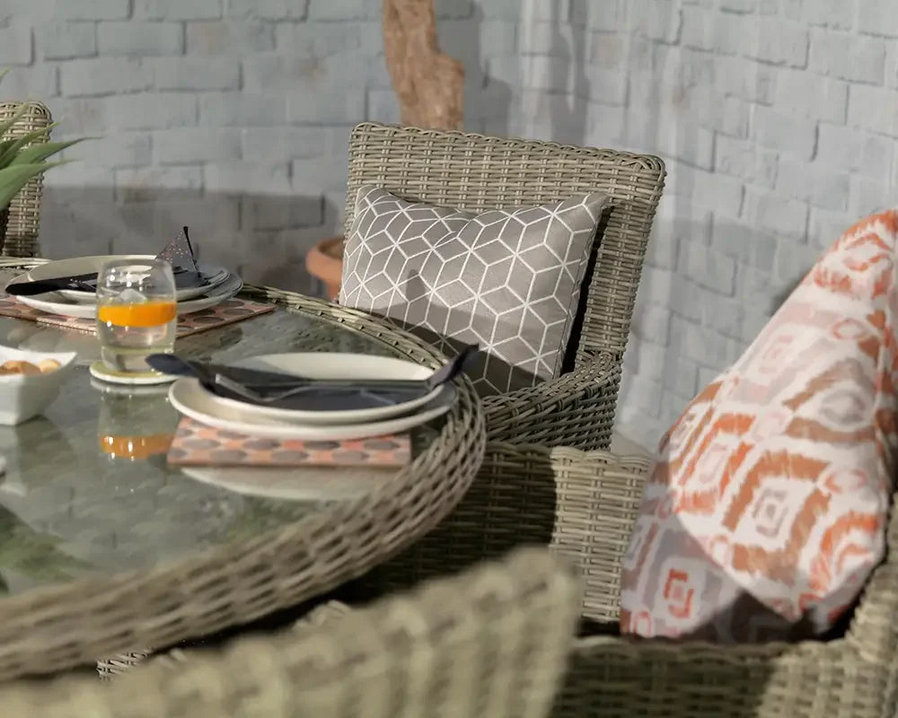 Rattan garden dining set with glass table, grey patterned cushion, outdoor place settings