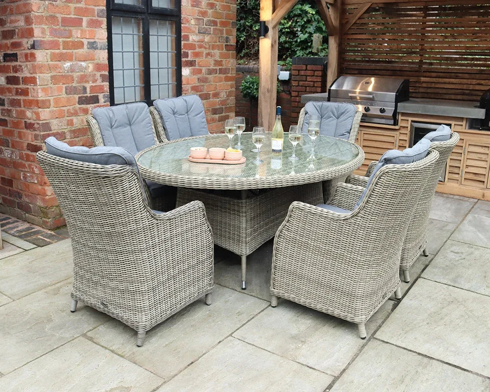 Rattan garden dining set with six cushioned chairs and glass top table on patio