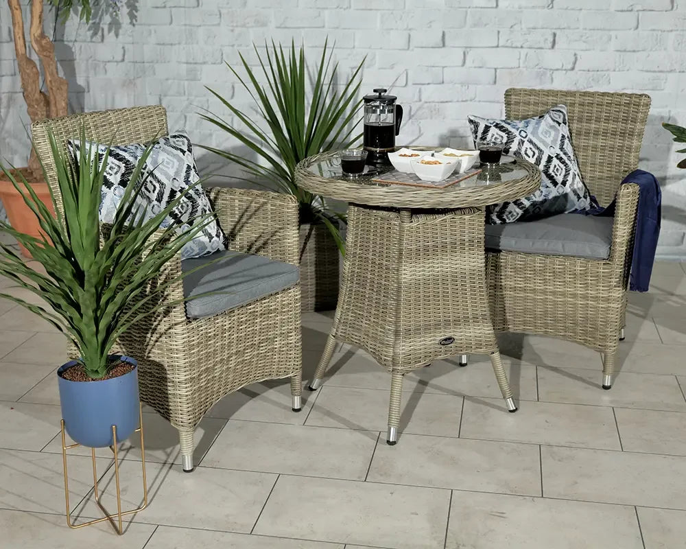 Rattan garden bistro set with grey cushions, glass top table and patterned throw pillows