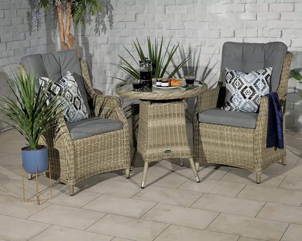 Rattan bistro set with two armchairs, grey cushions, and round table in patio setting