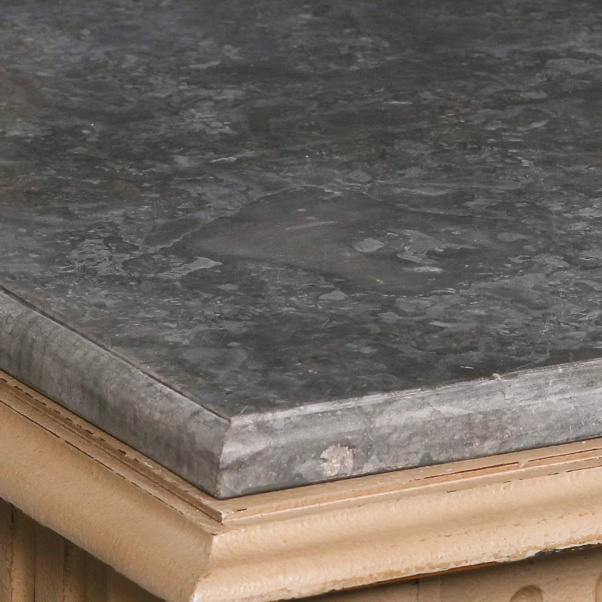 Dark marble table top with beige carved wood trim, close-up on material details