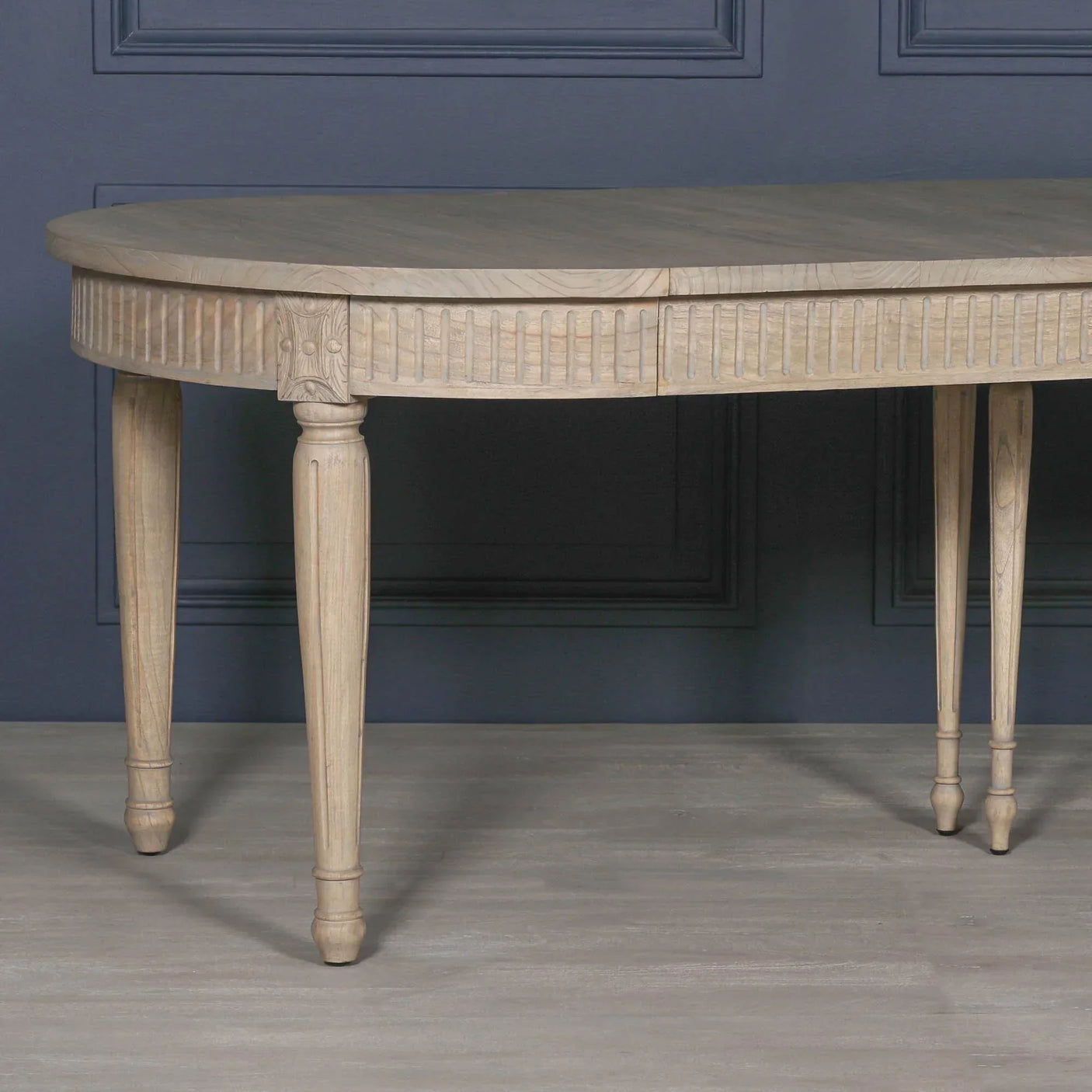 Half round wooden console table with fluted detailing and tapered legs against blue wall