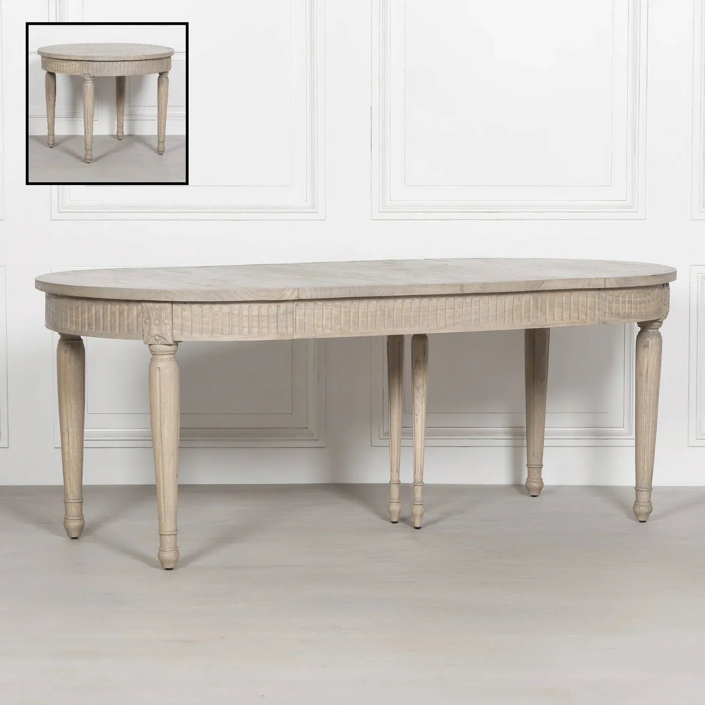 Oval wooden dining table with carved legs in light finish, shown with extension leaf