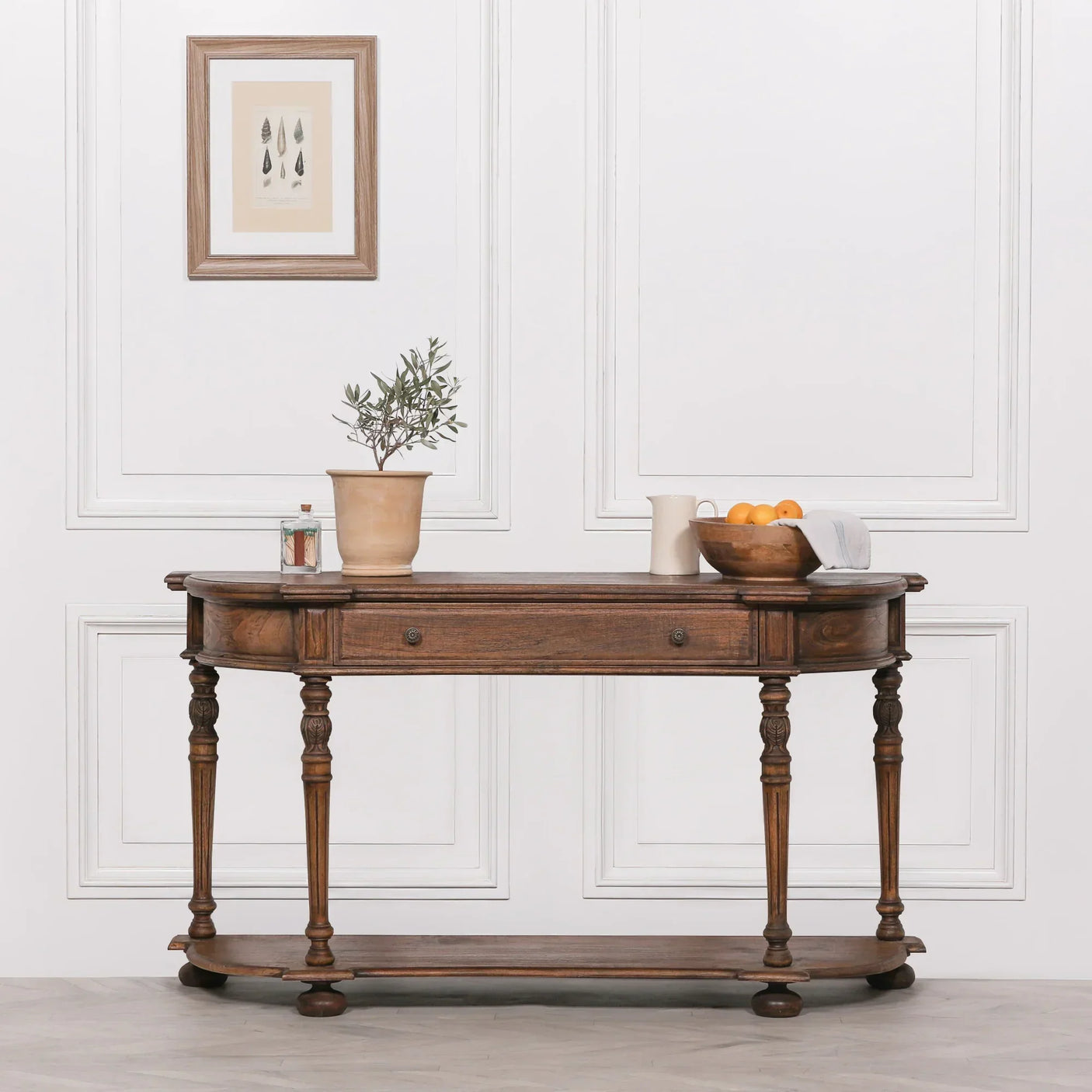 Oak console table with turned legs, drawer detail, and decorative items against white panel wall