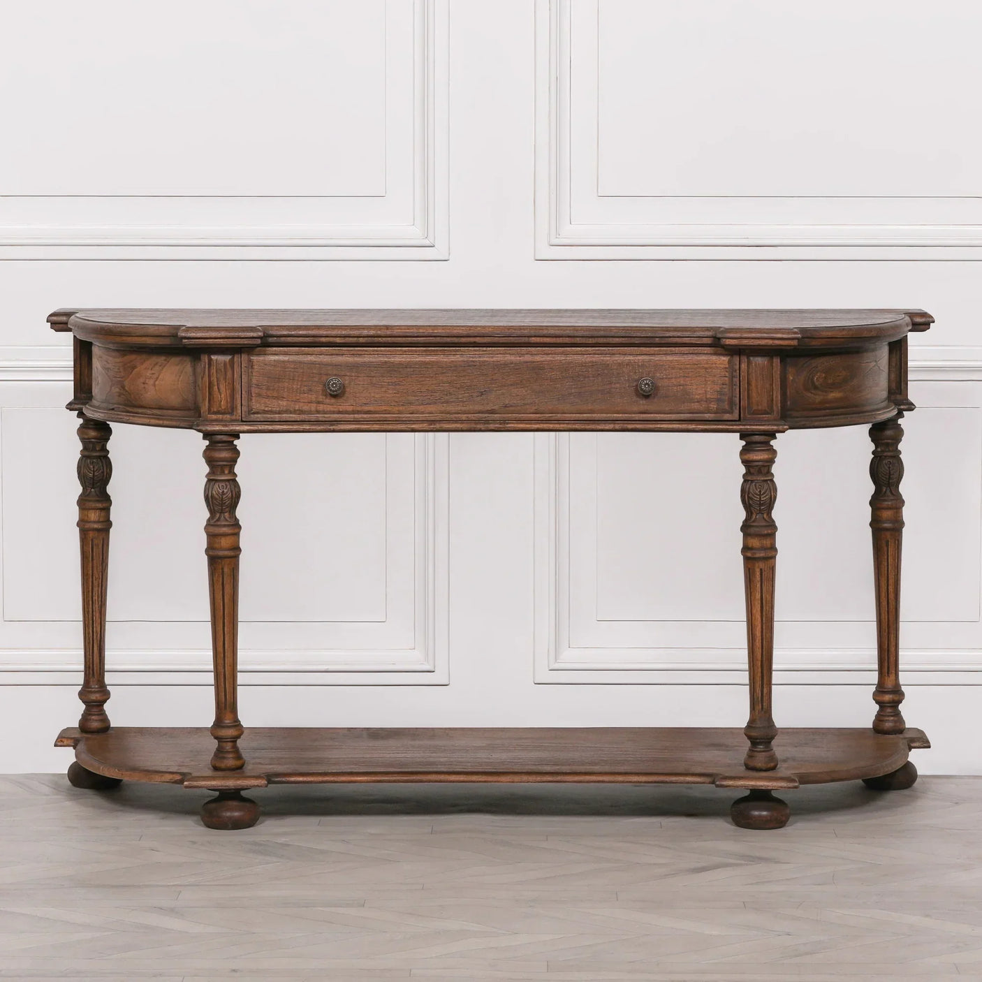 Dark wood console table with carved legs, central drawer and lower shelf against white wall