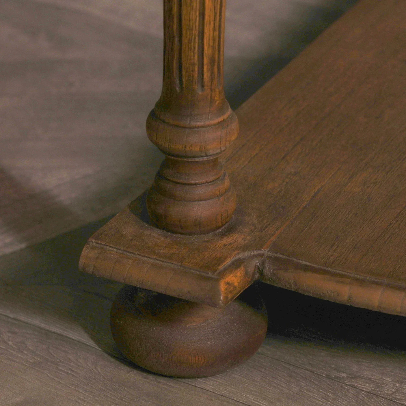 Close up of wooden table leg with carved detail on wood flooring