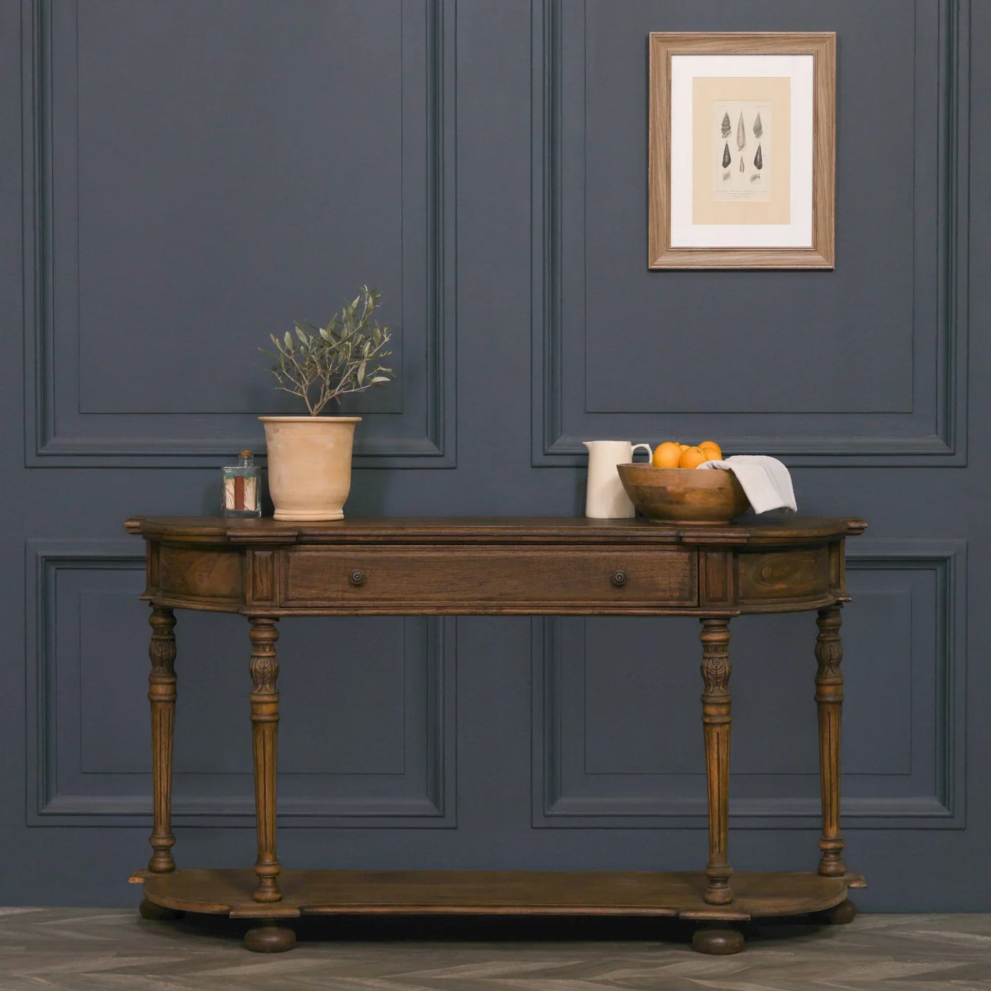 Classic wooden console table with drawers and shelf against dark blue paneled wall