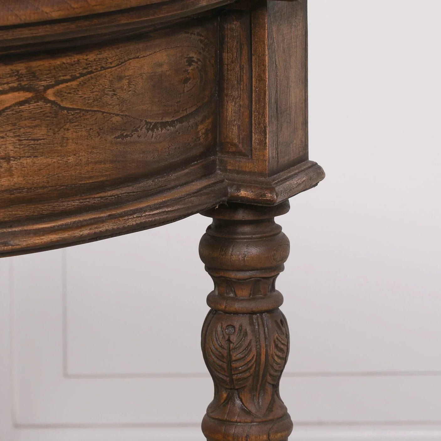 Carved wooden table leg with ornate detailing and rich brown finish