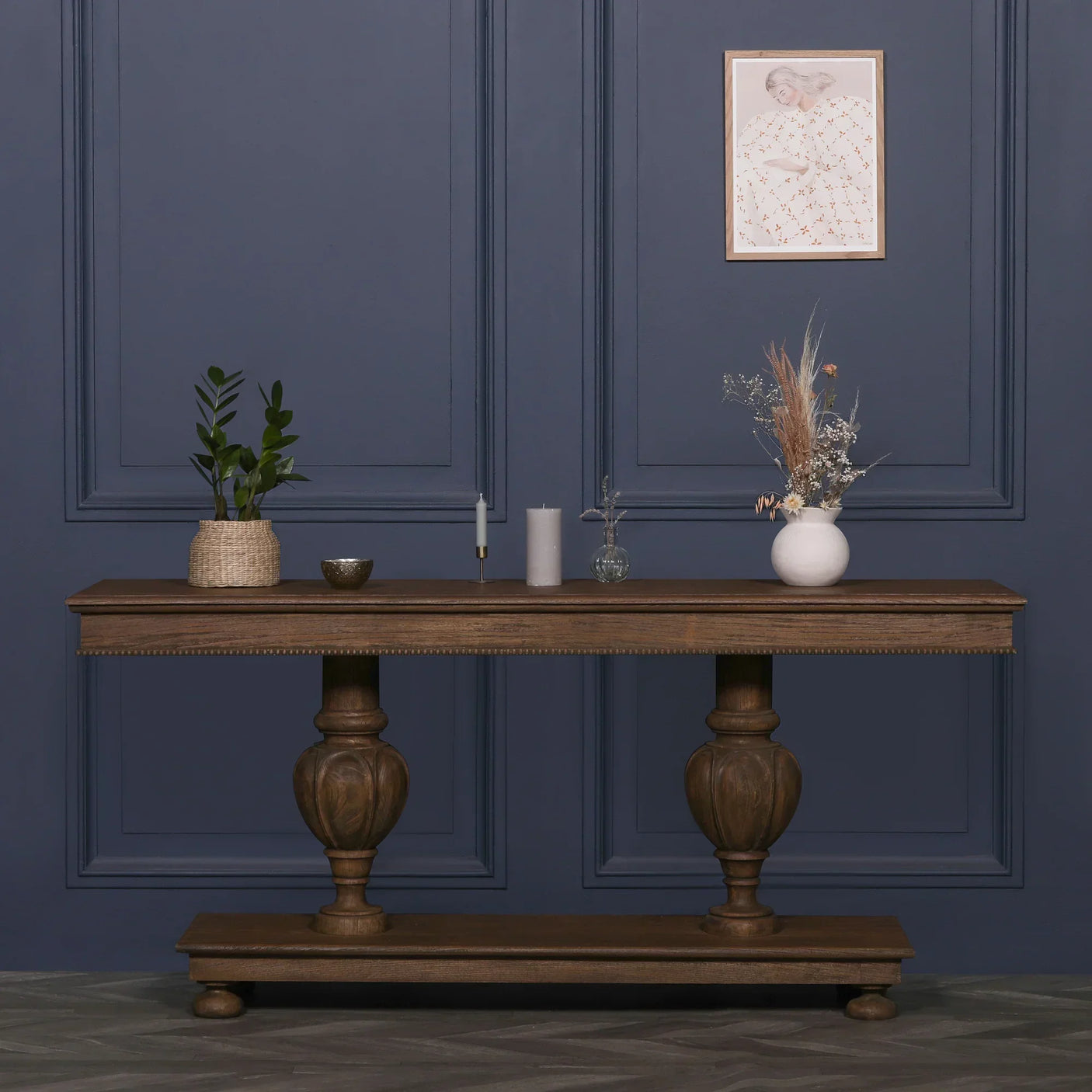 Rustic wooden console table with turned legs topped with plants, candles, and vase decor