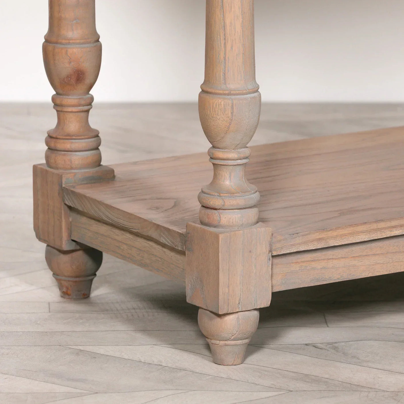 Turned wood coffee table legs with lower shelf on light wood herringbone floor