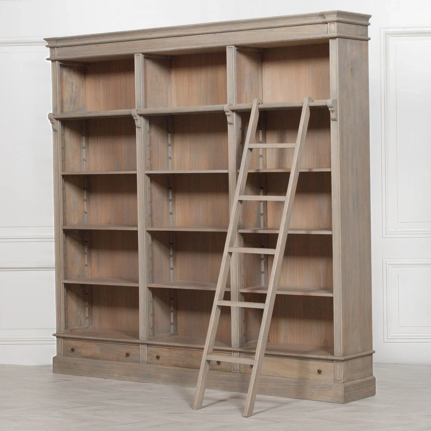 Large oak bookcase with adjustable shelves, ladder and lower drawers against white wall
