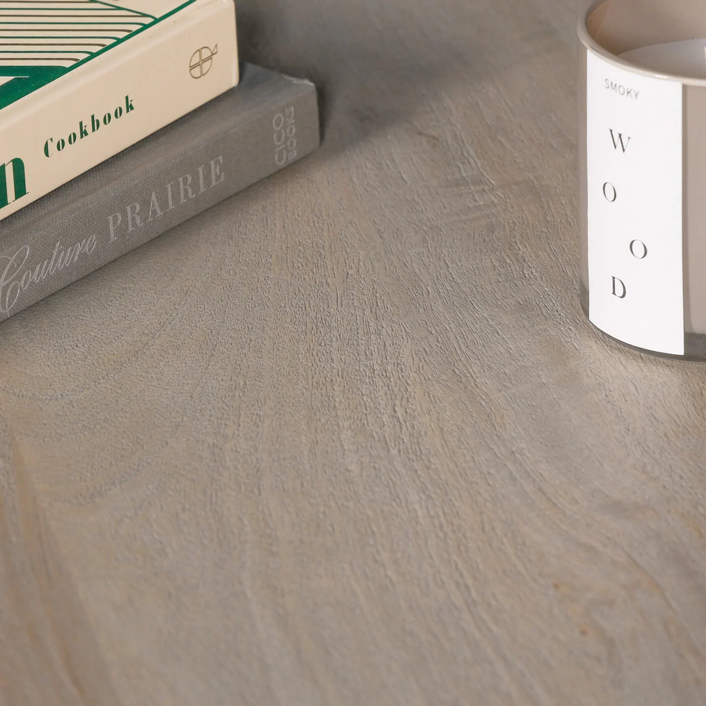 Light wood table surface with close view of grain, books, and candle in neutral decor style