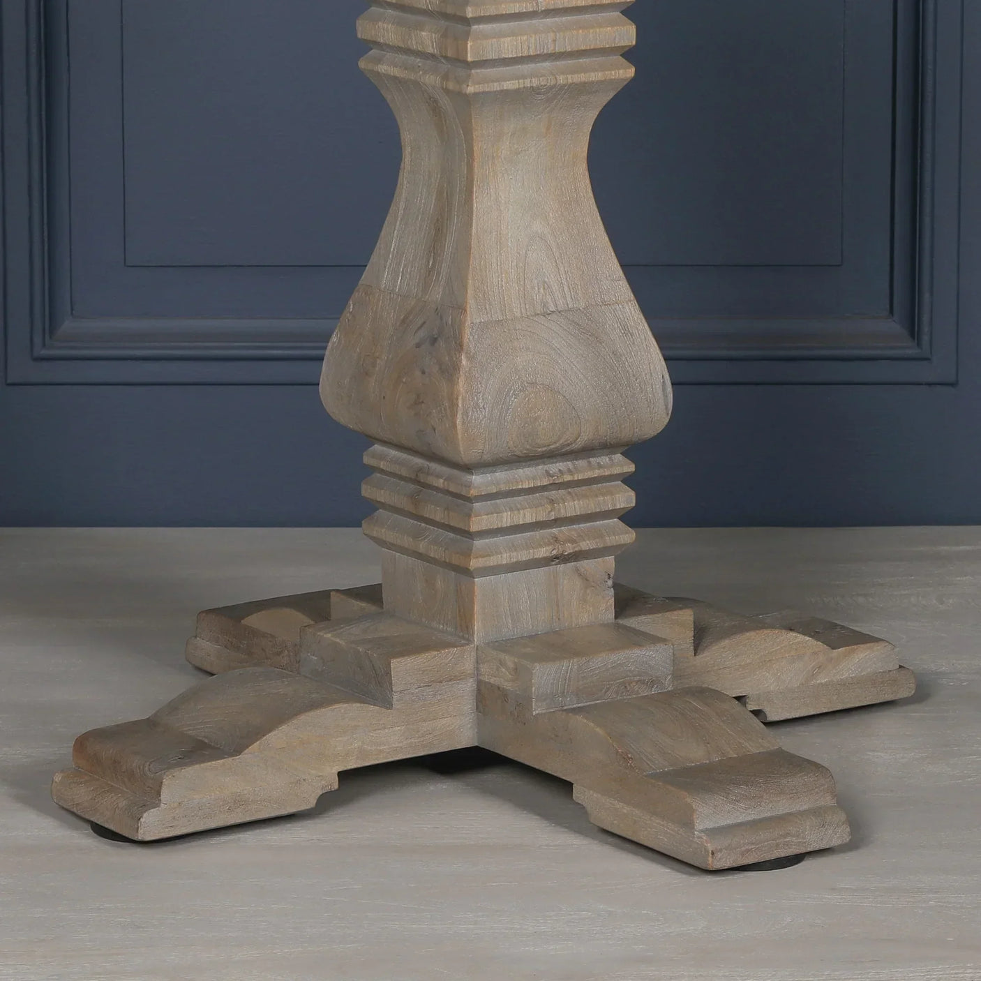 Solid wood dining table pedestal base with natural finish and carved details on floor