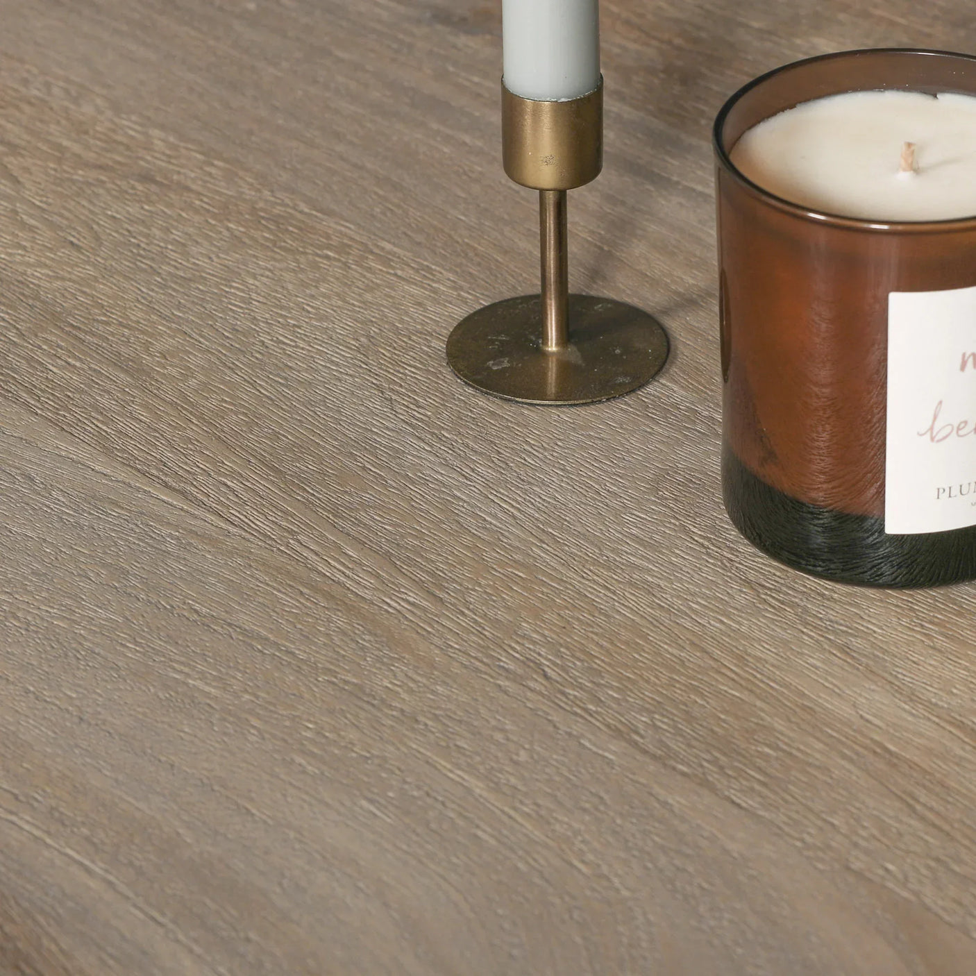 Light oak wood tabletop surface with candle holder and brown glass candle jar