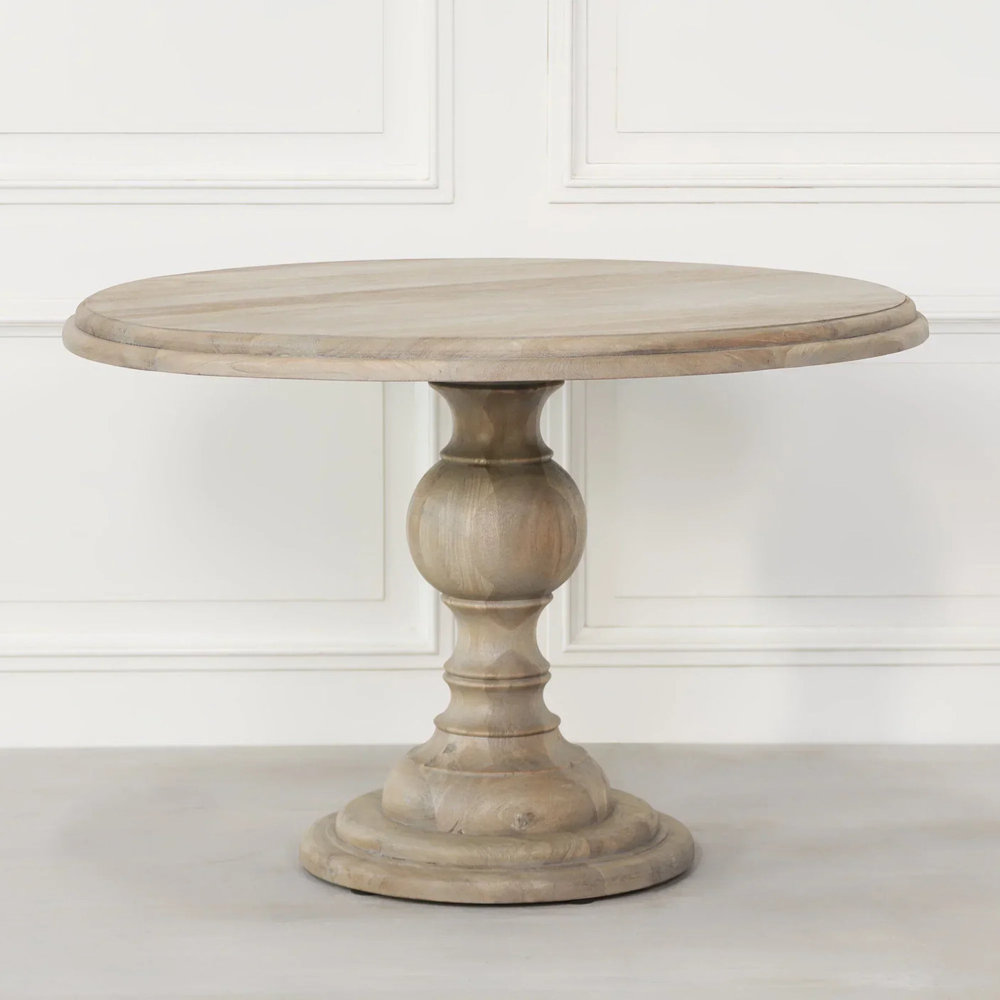 Round wooden dining table with pedestal base in light natural finish
