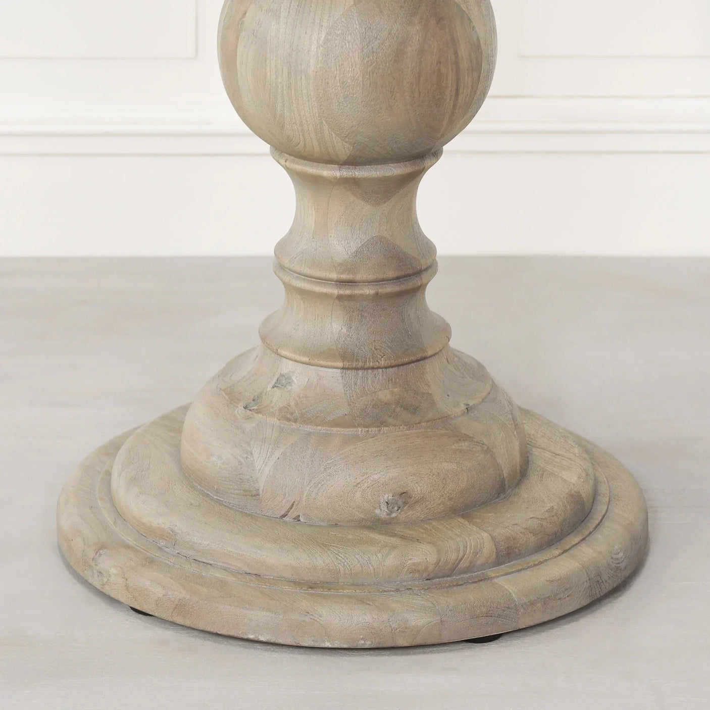 Round solid wood dining table pedestal base with natural finish, close-up view
