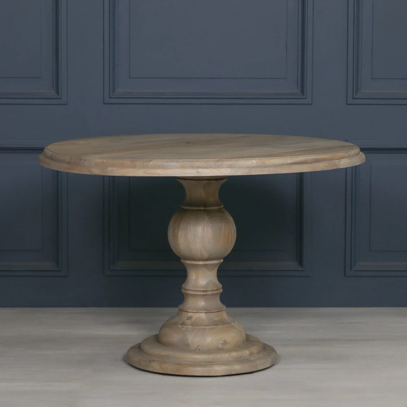 Round wooden dining table with pedestal base and natural finish