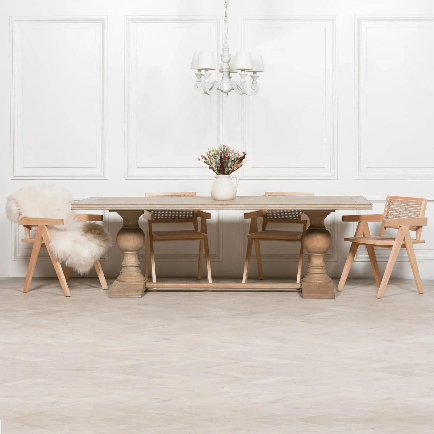Wood dining table with four cane back chairs and vase centerpiece in neutral room