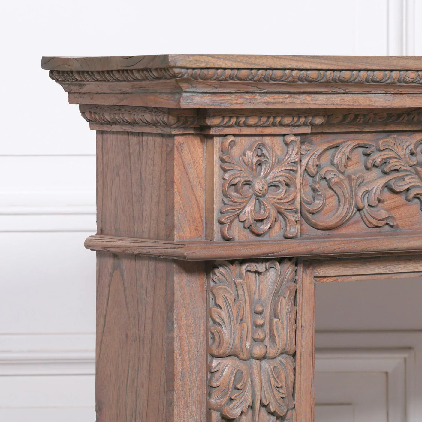Carved wooden fireplace surround with intricate floral and scrollwork detailing