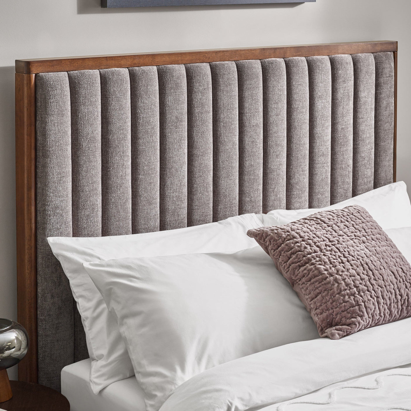 Close-up view of the rounded corner of the dark wooden frame of the bed's headboard