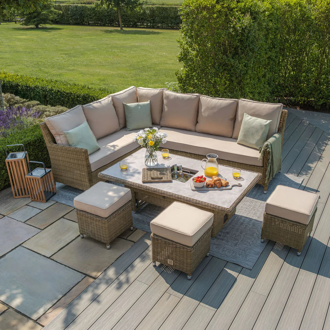 Rattan garden corner sofa set with beige cushions, dining table and stools on patio